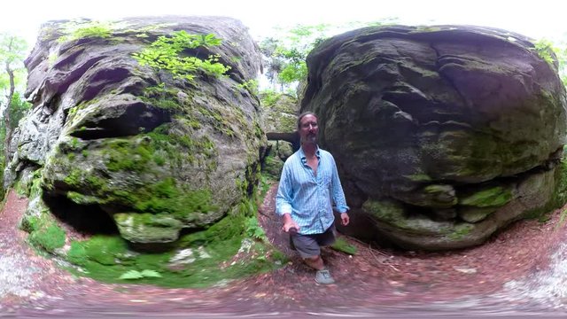 360 vr of mature man walking through a slot in large boulders.