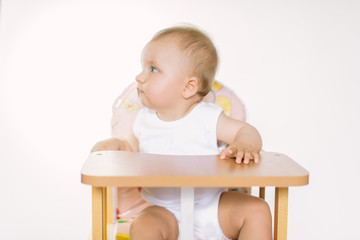 Portrait of a cute little girl smiling while sitting at table, isolated over white