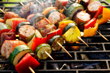 Grilled skewers of meat, sausages and various vegetables on a grill plate, outdoors, top view. Grilled food, bbq