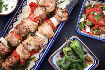 Traditional Greek souvlaki barbecue skewer with tomato onion salad and as closeup on a plate