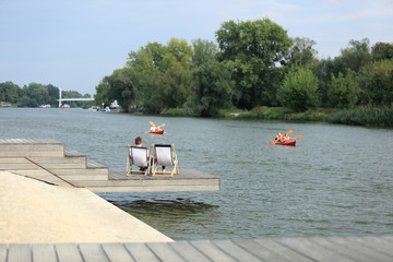 Para młodych ludzi odpoczywa na leżakach nad rzeką Odrą we Wrocławiu.