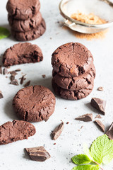 Chocolate cookies with pieces of chocolate and mint on a grey concrete background. Selective focus.