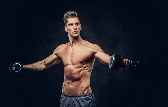 Handsome shirtless man with stylish hair and muscular ectomorph body doing the exercises with dumbbells.