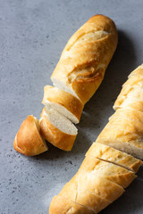 Sliced bread (baguette) over grey concrete background. Top view with copy space.