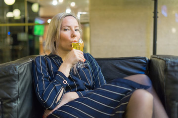 Young girl on a leather chair drinking white wine