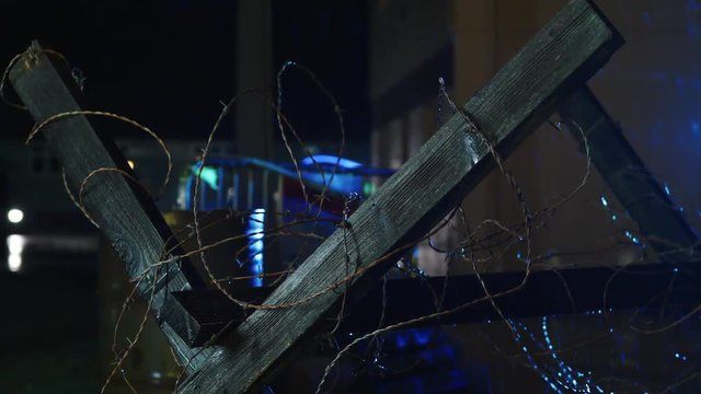Military style barbed wire barricade. A moody scene at night with rain and flashing warning lights.