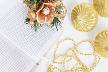 Romantic luxury Christmas and New Year decoration, golden balls, beads, opened day planner, on white table with copy space