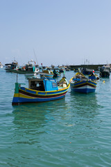 Fototapeta na wymiar Traditional colorful boats in the Harbor of Mediterranean fishing village Marsaxlokk, Malta