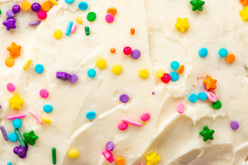 Close up of vanilla buttercream icing with colorful confetti sprinkles - obrazy, fototapety, plakaty