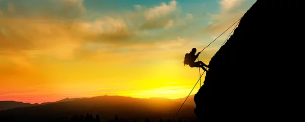 Poster Im Rahmen Silhouette einer schönen athletischen Frau, die einen steilen Felsen klettert © ginettigino