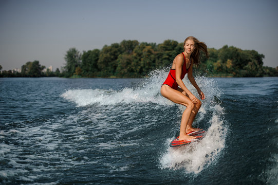 Blonde girl standing on the red wakeboard
