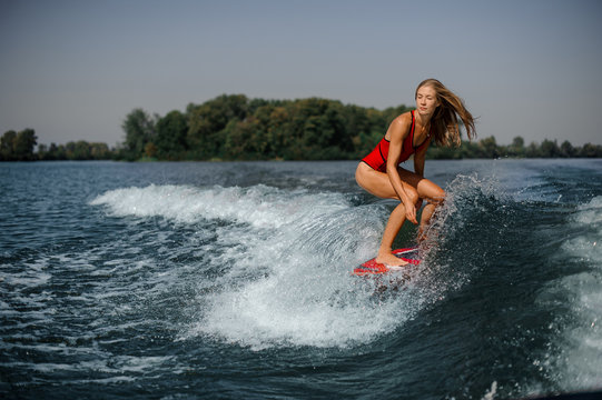 Blonde girl riding on the red wakeboard