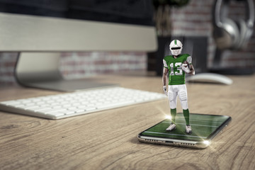Football Player with a green uniform playing and coming out of a full screen phone on a wooden table.