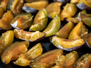 Plums cut in half laid in rows on a tray