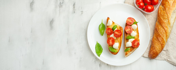 Bruschetta with tomatoes, mozzarella cheese and basil in a white plate. Traditional Italian snack or snack, antipasto. With space for writing.banner