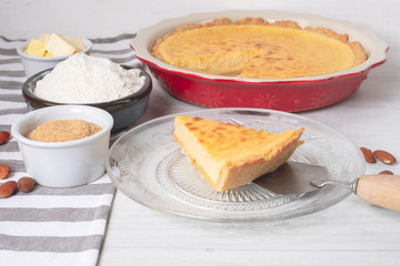 Baked sweet cake tart with cooking ingredients on kitchen table. Home cooking concept.