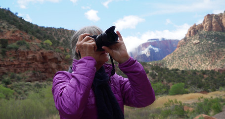 Senior female photographer taking pictures of sandstone canyon in Zion Utah