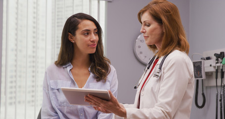 Portrait of lovely young hispanic woman meeting with senior doctor about pregnancy results. Close...