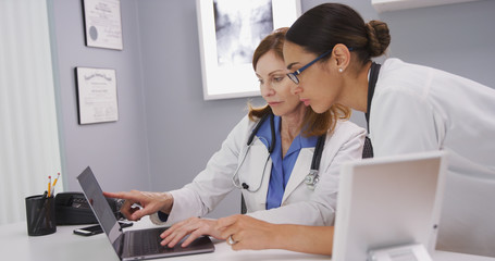 Portrait of two medical physicians looking at lab results of patient on laptop computer. Close up...