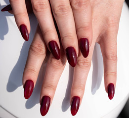 girl's fingers with a dark red manicure on a white background