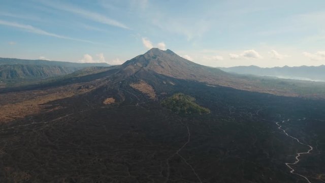 Volcano, mountains, sky with clouds, traces of lava on the ground. Aerial view of Mount Batur Volcano in Kintamani. Bali volcano, also referred to as Kintamani is popular sightseeing destination in