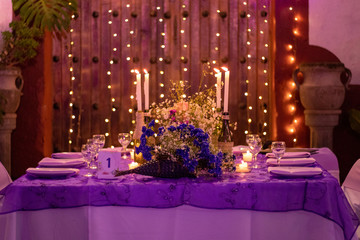Party table decorated with lights in the background and candles