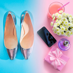 Composition flat lay gift to a woman Modern gadget mobile phone glass cocktail perfume bouquet of flowers Preparing for holiday surprise gift box shoes Top view pink blue background