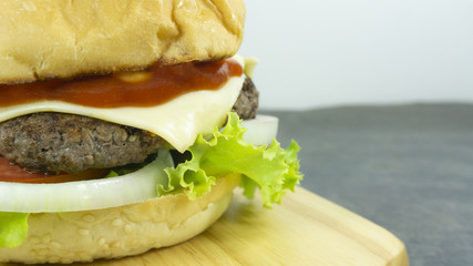 Burger beef cheese in a Chopping Wood props decoration with Green salad, tomato and sausage Rust stone wall or grunge stone texture on background, Copy space..