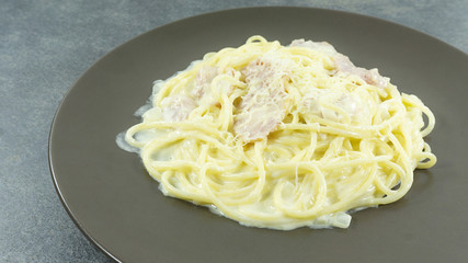 Spaghetti Carbonara in a Brown plate with Bacon and milk line yellow on a stone floor table,Front view, Copy space Close up..