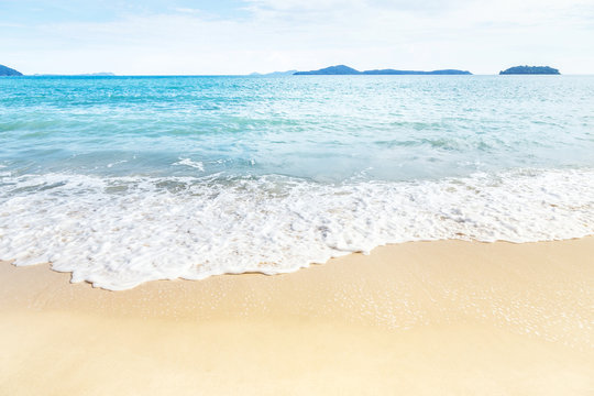 Fototapeta white soft wave rolling splash on empty tropical sandy beach in sunny day