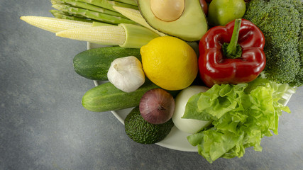 Vegetarian bowl Healthy food Onion, red pepper, tomato, Bell pepper, lemon, cauliflower, cucumber, avocado, carrot, green salads, sweet corn on a rock stone background Top view..