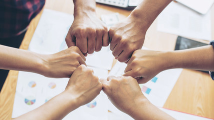 close up hand of business partnerships people bump hands finishing up meeting showing unity over office desk , business teamwork concept
