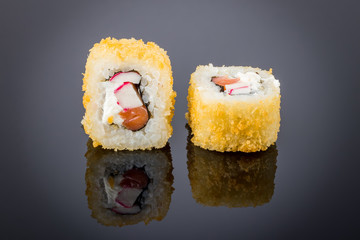 Hot roll with tempura crab on black with reflection