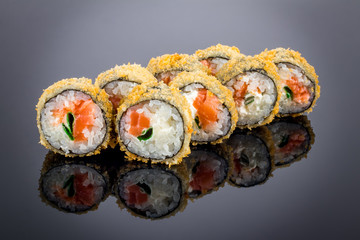 Hot roll with salmon tempura on black with reflection
