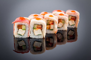 chicken and bacon sushi roll on black with reflection