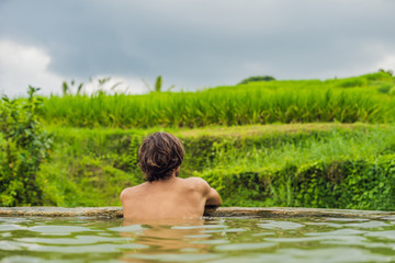 Fototapeta premium Man tourist in Belulang Hot Springs in Bali on the background of rice terraces