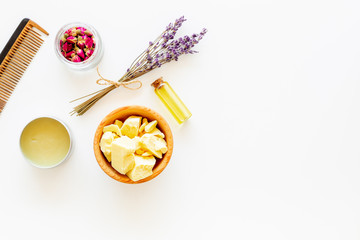 Hair treatment with natural products. Jojoba, argan, coconut oil near bunch of lavender and hairbrush on white background top view copy space