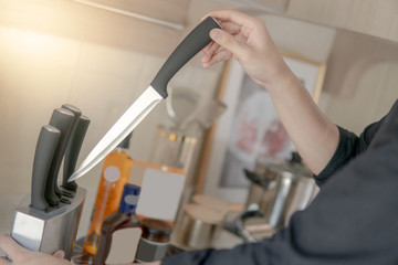 Male hand choosing knife from the set on vintage kitchen counter. Home living lifestyle in the kitchen.