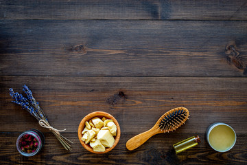 Natural oil for hair. Jojoba, argan, coconut oil near bunch of lavender and hairbrush on dark wooden background top view copy space