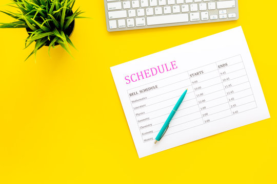 School student's schedule with time of lessons on yellow office desk with computer keyboard top view copy space