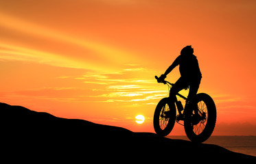 Fototapeta premium Silhouette man and bike relaxing on blurry sky background.