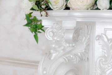 White fireplace in classic style with a forged black grill, decorated with flowers.