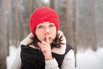 Fototapeta na wymiar Portrait of girl in a red cap and warm jacket in the forest in a winter