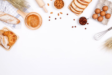 Homemade breads or bun, croissant and bakery ingredients, flour, almond nuts, hazelnuts, eggs on white background, Bakery background frame, Cooking breakfast concept. Flat lay, Top view and copy space