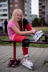 active lifestyle in a modern city - girl puts on roller skates at the stadium