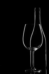 Empty glass bottle with glass isolated on a black background. Copyspace
