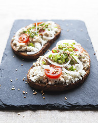 Smorrebrod. Traditional Danish open sandwich with cheese, forshmak, tomatoes, onions and sesame seeds.