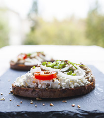 Smorrebrod. Traditional Danish open sandwich with cheese, forshmak, tomatoes, onions and sesame seeds.