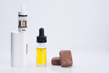 white electronic cigarette, next to a glass refill liquid for refilling, with a taste of chocolate candy