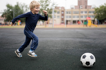 active lifestyle in a modern city - little boy playing with a soccer ball at the stadium